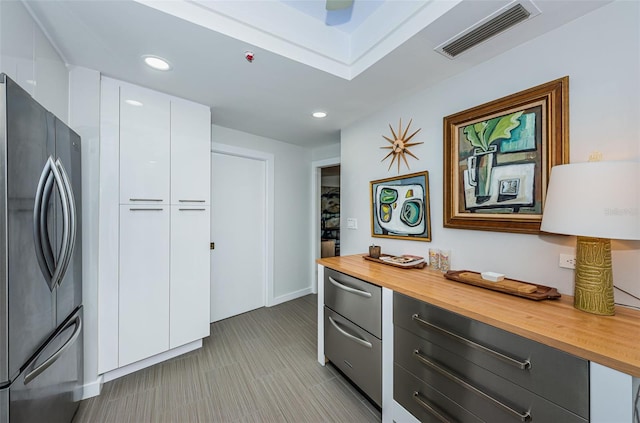 kitchen featuring gray cabinets, light tile floors, white cabinets, wood counters, and stainless steel refrigerator