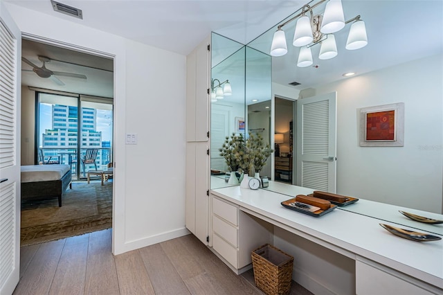 bathroom with ceiling fan with notable chandelier and hardwood / wood-style flooring