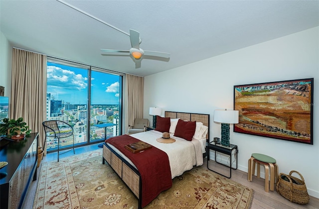 bedroom with a wall of windows, ceiling fan, access to outside, and light wood-type flooring