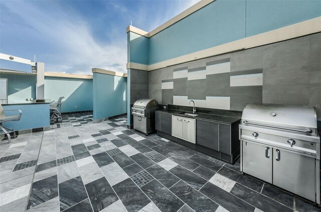 view of patio with exterior kitchen, area for grilling, and sink