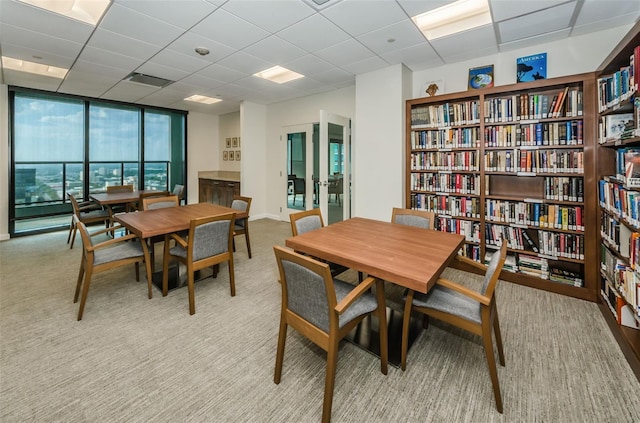 carpeted dining area featuring a paneled ceiling