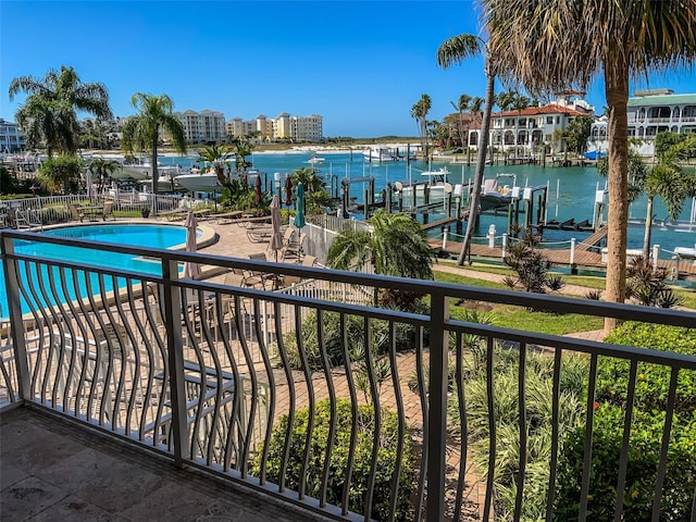 balcony featuring a water view, a community pool, and a boat dock