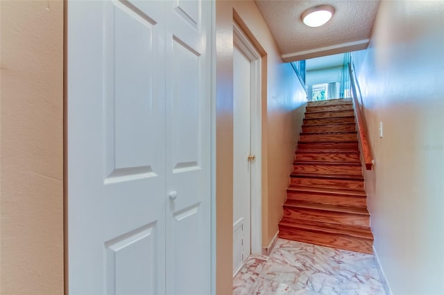 staircase featuring a textured ceiling and light tile floors