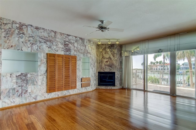 unfurnished living room featuring a large fireplace, ceiling fan, hardwood / wood-style flooring, and track lighting