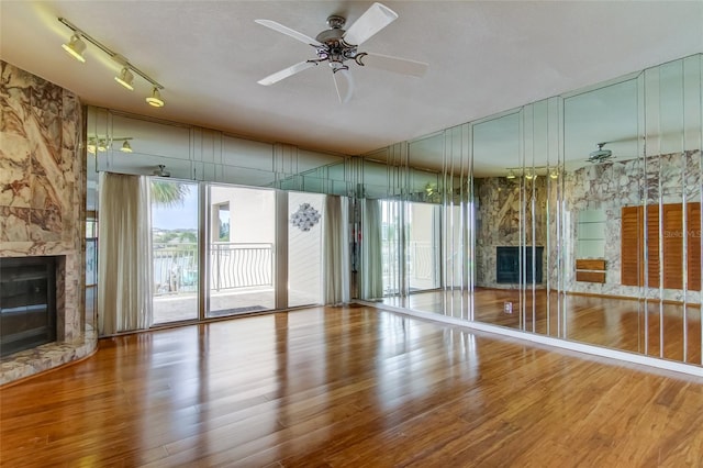 unfurnished living room with track lighting, plenty of natural light, light hardwood / wood-style floors, and a fireplace