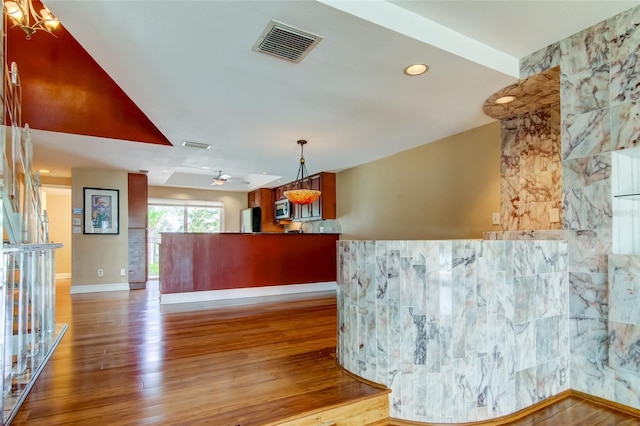 interior space with hardwood / wood-style floors, refrigerator, hanging light fixtures, and ceiling fan with notable chandelier