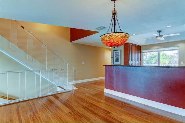 interior space featuring ceiling fan, light hardwood / wood-style floors, and decorative light fixtures