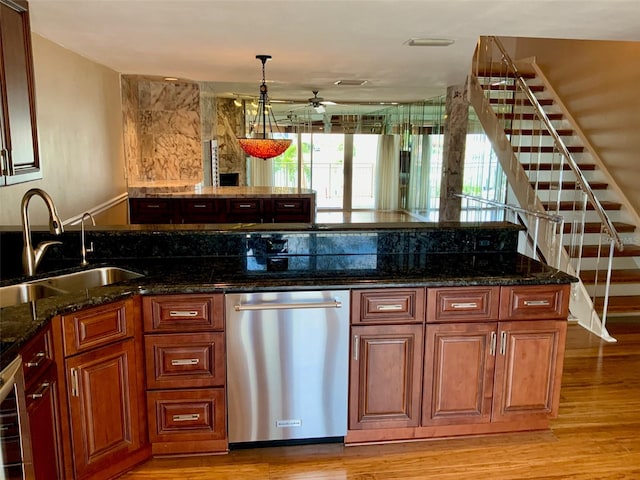 kitchen featuring sink, light wood-type flooring, dark stone countertops, and stainless steel dishwasher