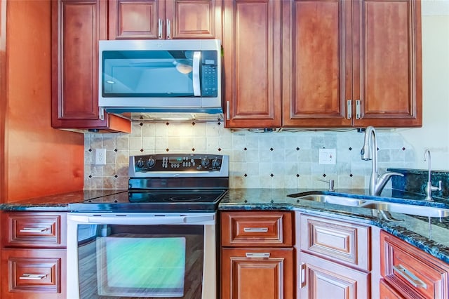 kitchen with appliances with stainless steel finishes, backsplash, dark stone counters, and sink