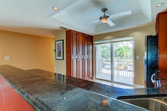 kitchen with a raised ceiling, ceiling fan, and refrigerator