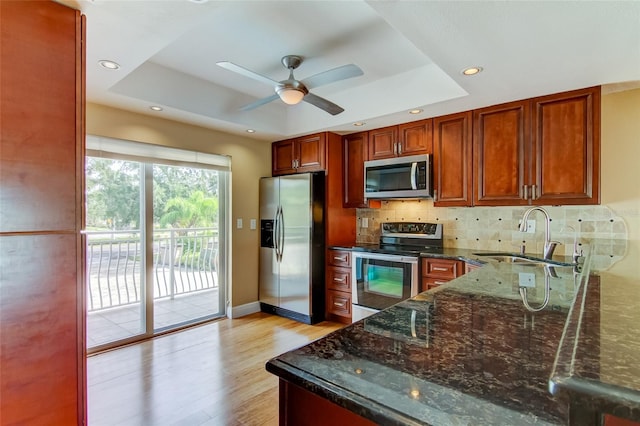 kitchen featuring stainless steel appliances, ceiling fan, tasteful backsplash, a raised ceiling, and sink