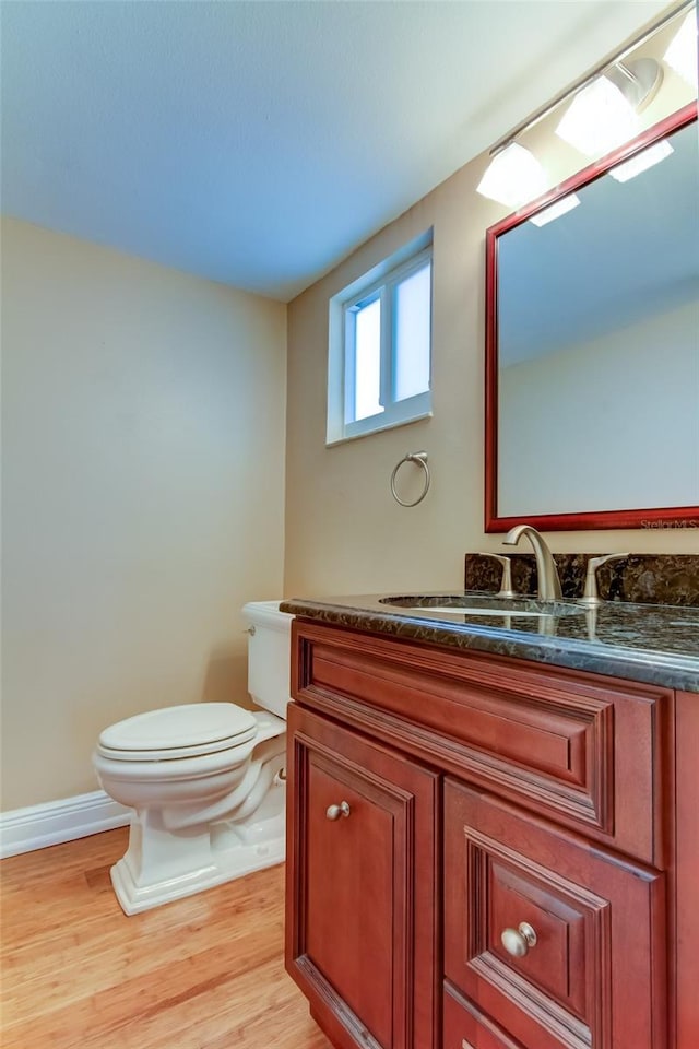 bathroom with toilet, hardwood / wood-style floors, and vanity