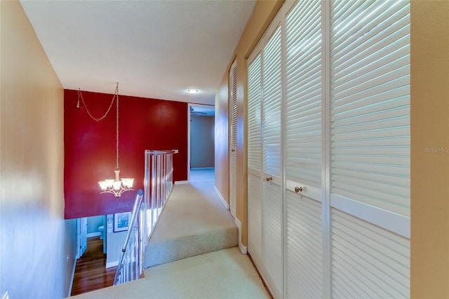 hall with an inviting chandelier and light colored carpet