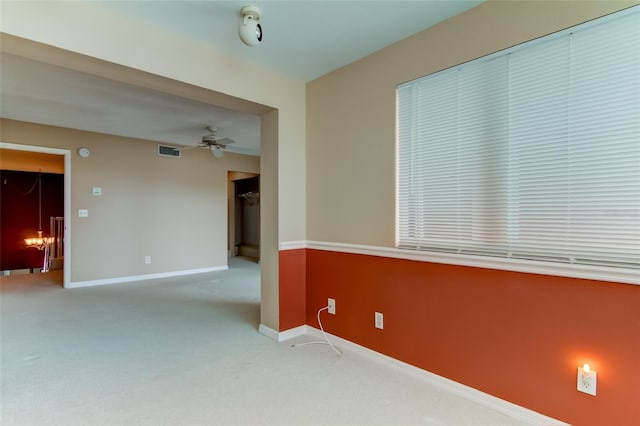 spare room with light colored carpet and ceiling fan with notable chandelier