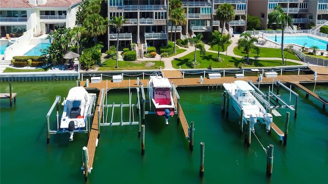 view of dock with a water view, a community pool, and a balcony