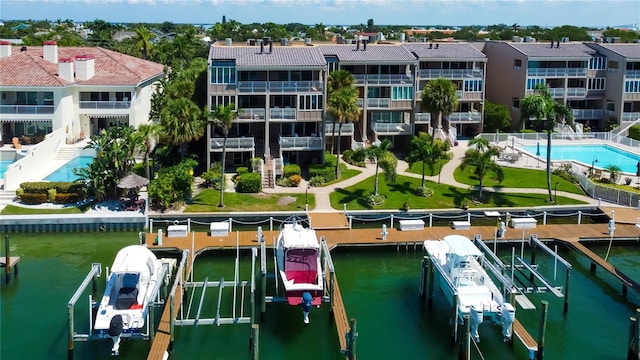 view of dock featuring a balcony, a community pool, and a water view