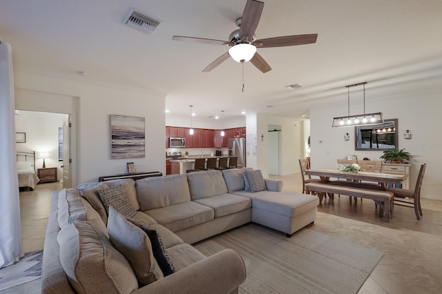 tiled living room featuring ceiling fan with notable chandelier