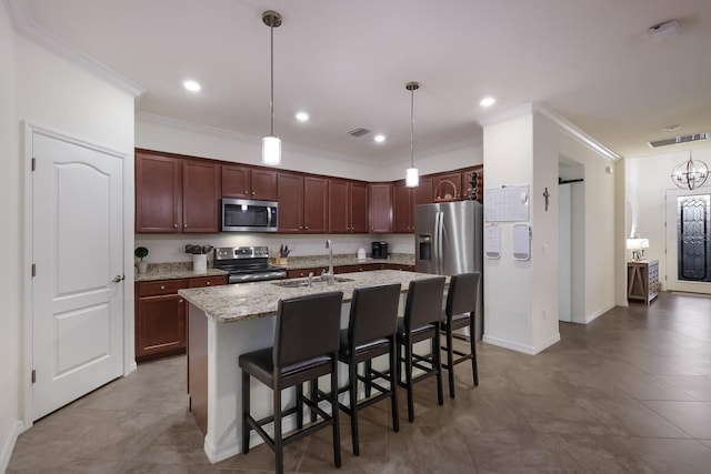 kitchen featuring sink, a kitchen breakfast bar, appliances with stainless steel finishes, a center island with sink, and decorative light fixtures