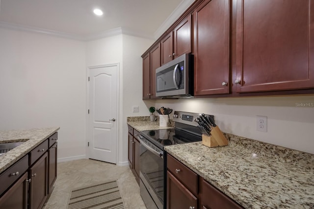 kitchen with light stone countertops, ornamental molding, stainless steel appliances, and light tile floors