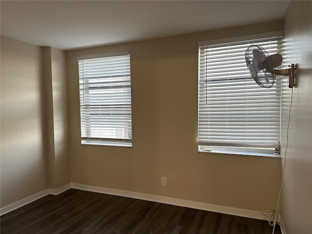 spare room with baseboards and dark wood finished floors