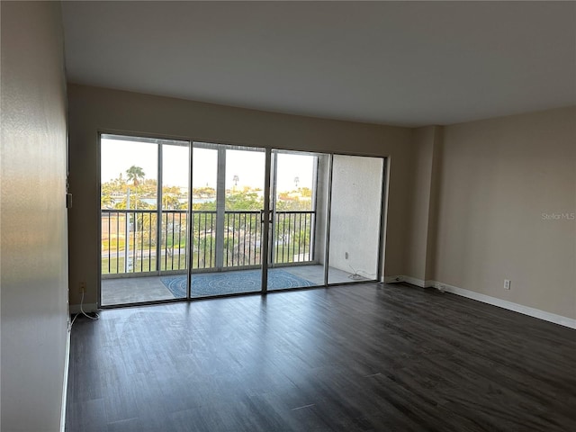 spare room featuring dark wood-type flooring and baseboards