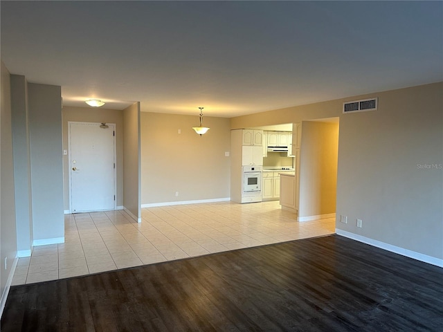 unfurnished living room featuring visible vents, light wood-style flooring, and baseboards