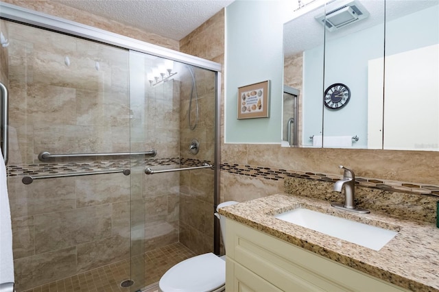 bathroom featuring toilet, a shower with door, vanity, backsplash, and a textured ceiling