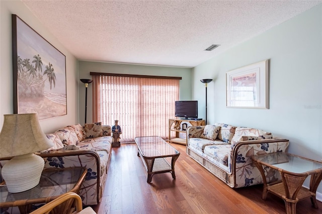 living room with a textured ceiling and dark hardwood / wood-style flooring