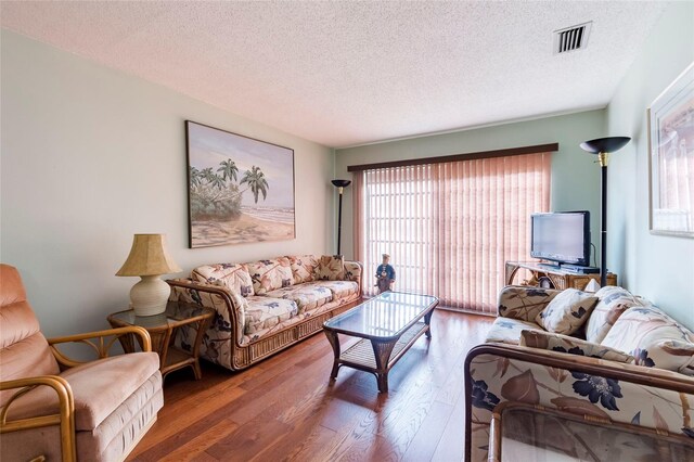 living room with dark hardwood / wood-style floors, a textured ceiling, and a healthy amount of sunlight