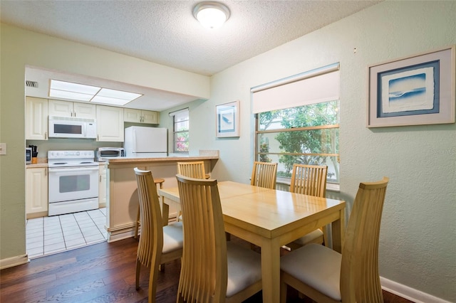 dining area featuring dark tile flooring, a textured ceiling, and a skylight