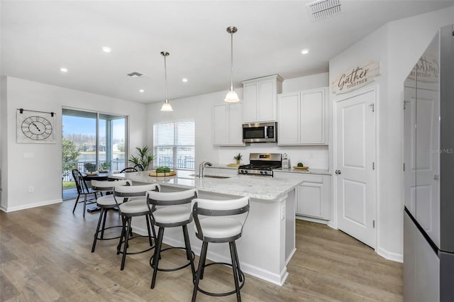 kitchen featuring appliances with stainless steel finishes, sink, a kitchen island with sink, and white cabinets