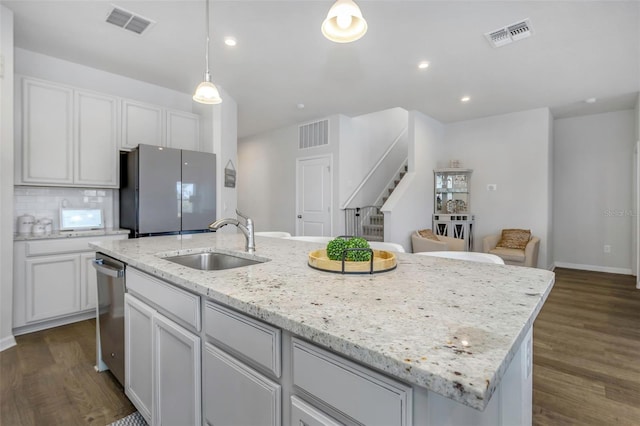 kitchen featuring sink, hanging light fixtures, stainless steel dishwasher, and an island with sink