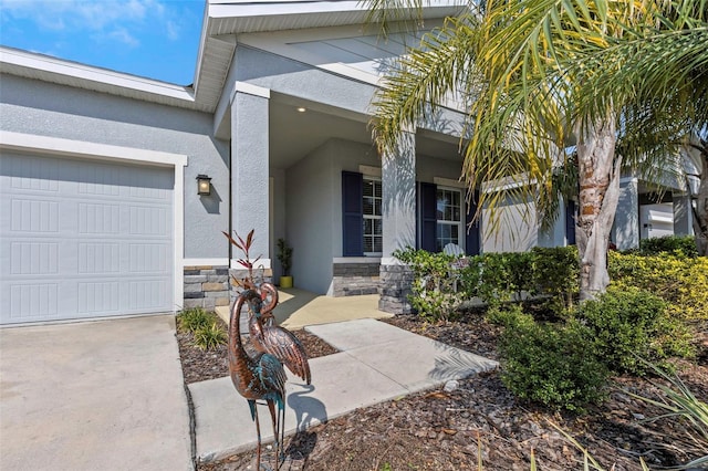 doorway to property featuring an attached garage, covered porch, stone siding, and stucco siding