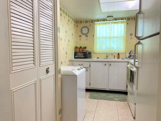 clothes washing area with light tile floors, sink, and washer / dryer