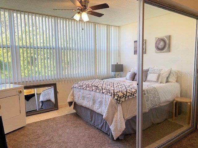 bedroom with a textured ceiling, washer / dryer, ceiling fan, and light tile flooring