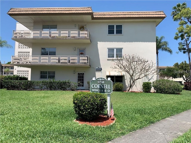 rear view of property with a lawn and a balcony