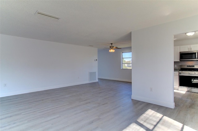 unfurnished room with a textured ceiling, ceiling fan, and light hardwood / wood-style flooring