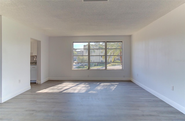 unfurnished room with light hardwood / wood-style floors and a textured ceiling