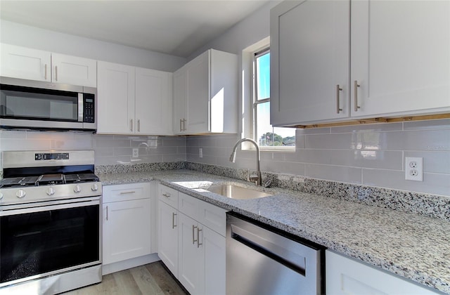 kitchen featuring tasteful backsplash, stainless steel appliances, white cabinets, and light hardwood / wood-style flooring