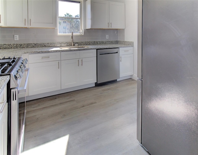 kitchen featuring white cabinets, appliances with stainless steel finishes, backsplash, and light hardwood / wood-style flooring