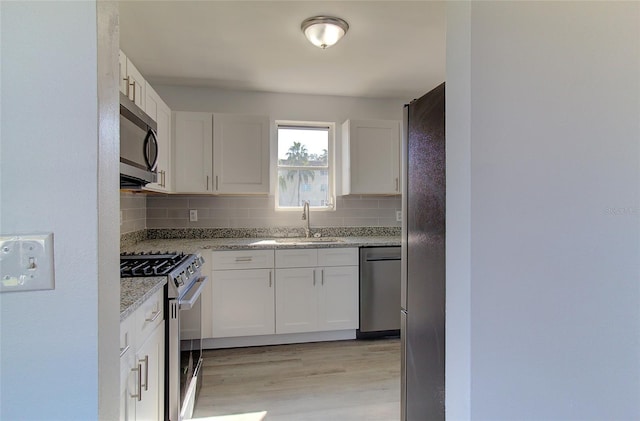 kitchen featuring light hardwood / wood-style floors, sink, stainless steel appliances, white cabinets, and tasteful backsplash