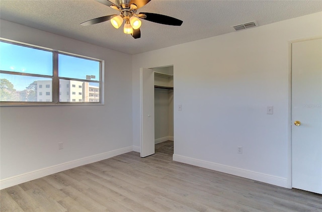 unfurnished bedroom featuring a closet, a textured ceiling, ceiling fan, and light hardwood / wood-style flooring