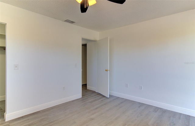 spare room featuring light hardwood / wood-style floors, ceiling fan, and a textured ceiling