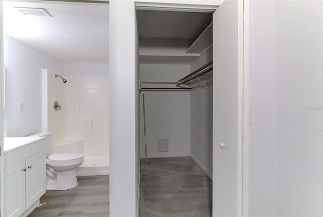 bathroom featuring walk in shower, toilet, vanity, and hardwood / wood-style flooring