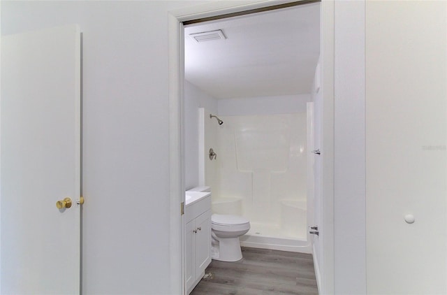 bathroom with a shower, toilet, hardwood / wood-style floors, and vanity