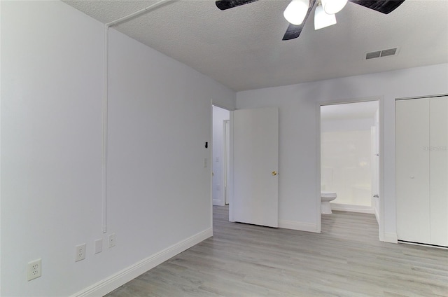 unfurnished bedroom featuring connected bathroom, light hardwood / wood-style floors, ceiling fan, and a textured ceiling