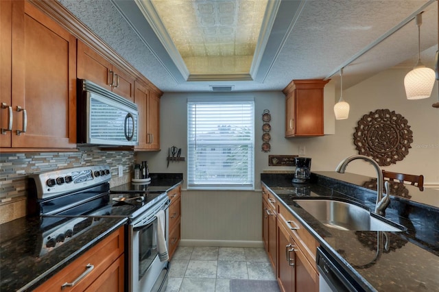 kitchen featuring appliances with stainless steel finishes, a textured ceiling, hanging light fixtures, sink, and dark stone countertops