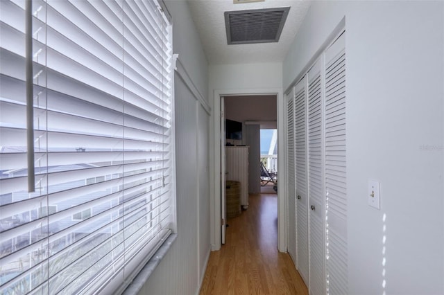 hallway with hardwood / wood-style floors and a textured ceiling