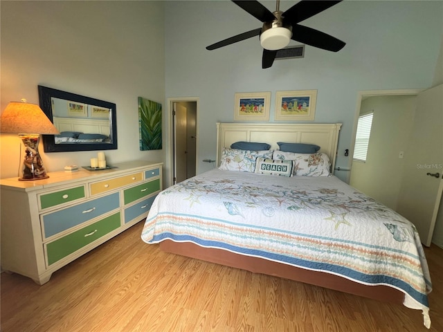 bedroom featuring light wood-type flooring, ceiling fan, and a high ceiling