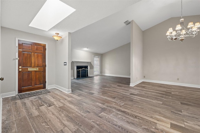 foyer entrance featuring an inviting chandelier, vaulted ceiling with skylight, and hardwood / wood-style floors